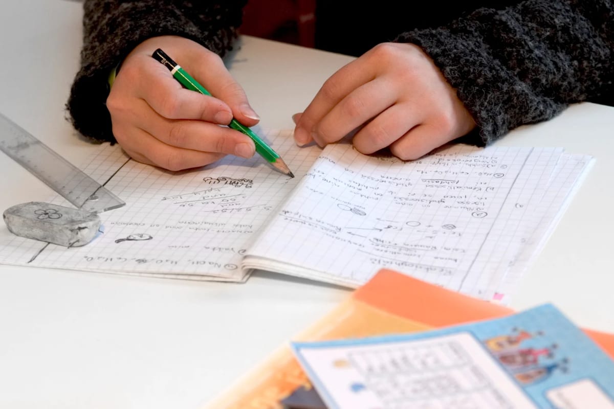 A student working carefully through a math problem by hand